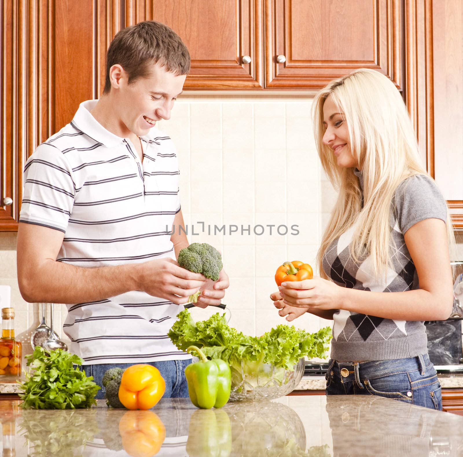 Young couple in the kitchen have fun while making a fresh salad. Square shot.