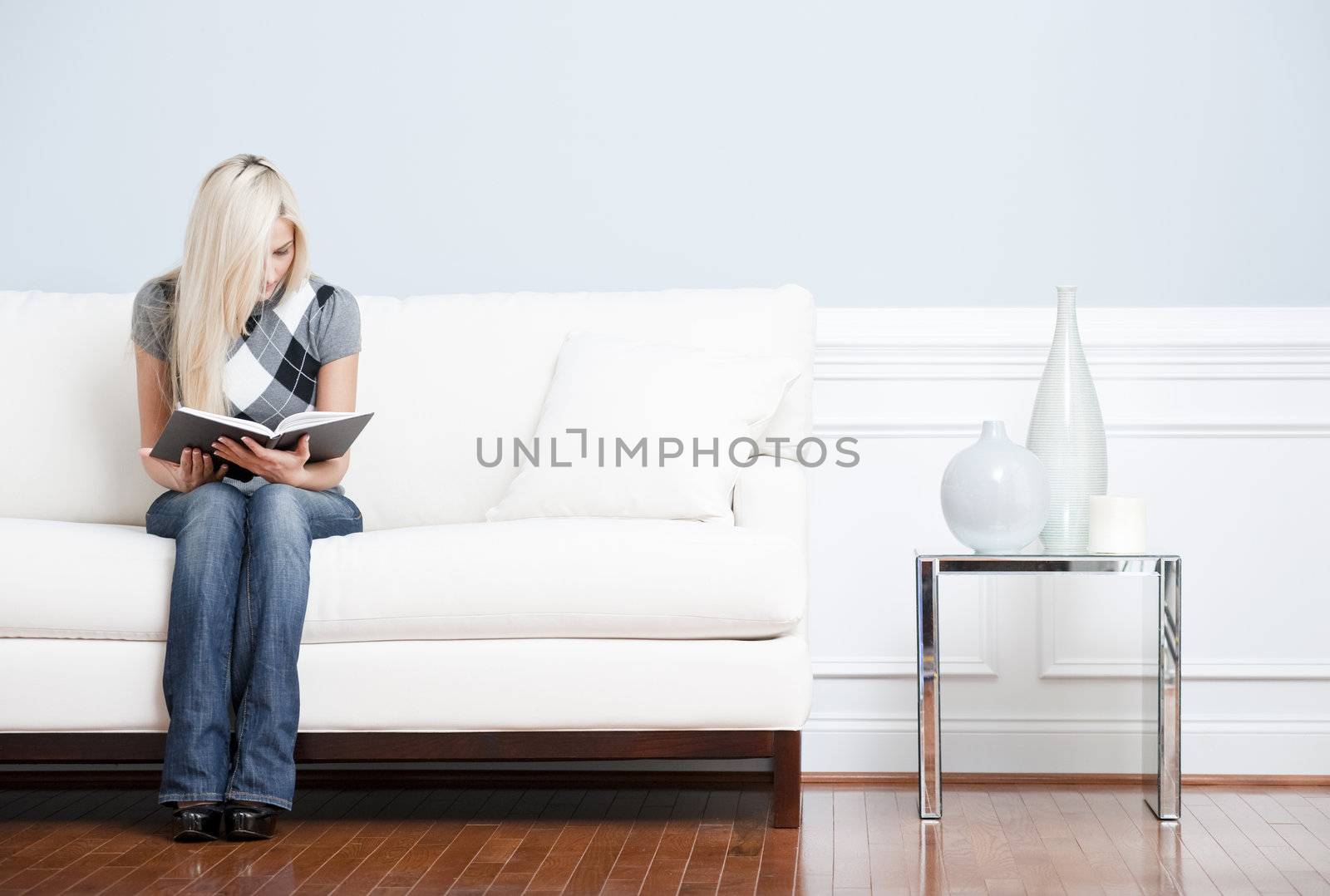 Young Woman Sitting on Sofa Reading by cardmaverick