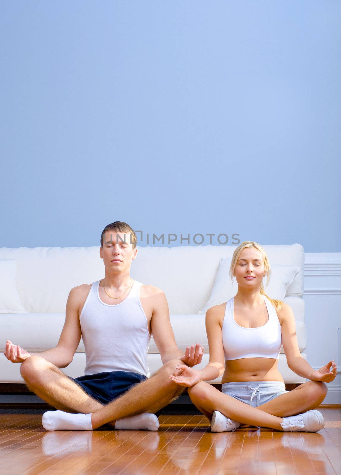 Young Couple Sitting on Floor Meditating by cardmaverick