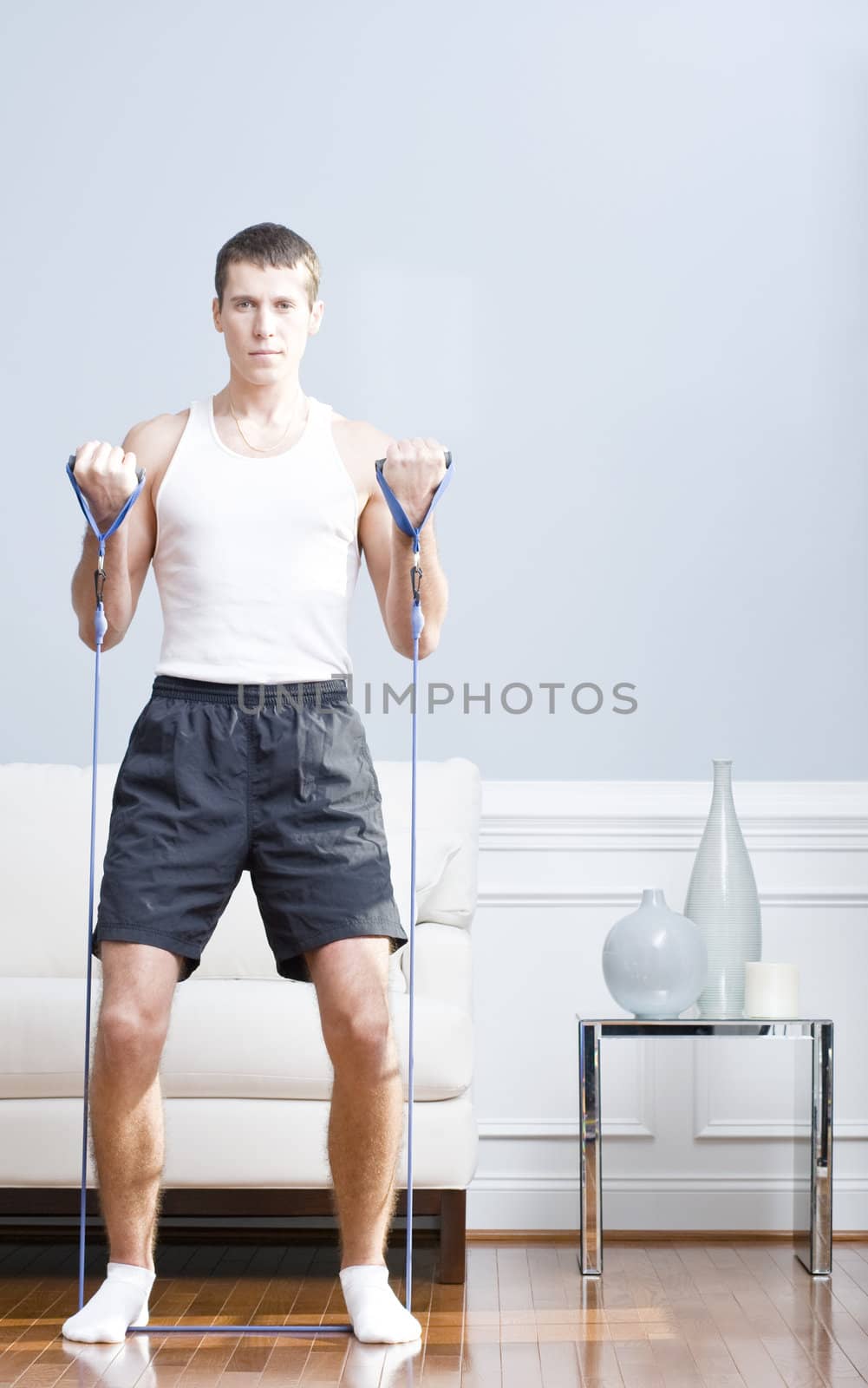 Man standing and using resistance bands in his living room. Vertical format.