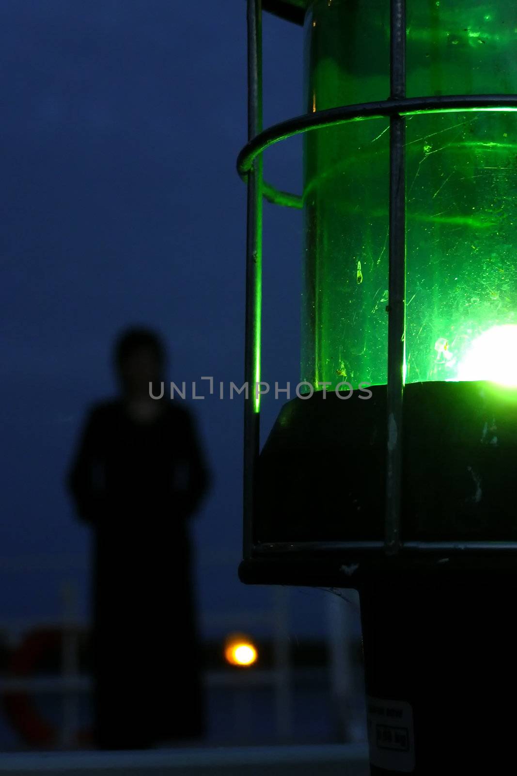 silhouette of woman on a nightly deck with a green lantern on a foreground