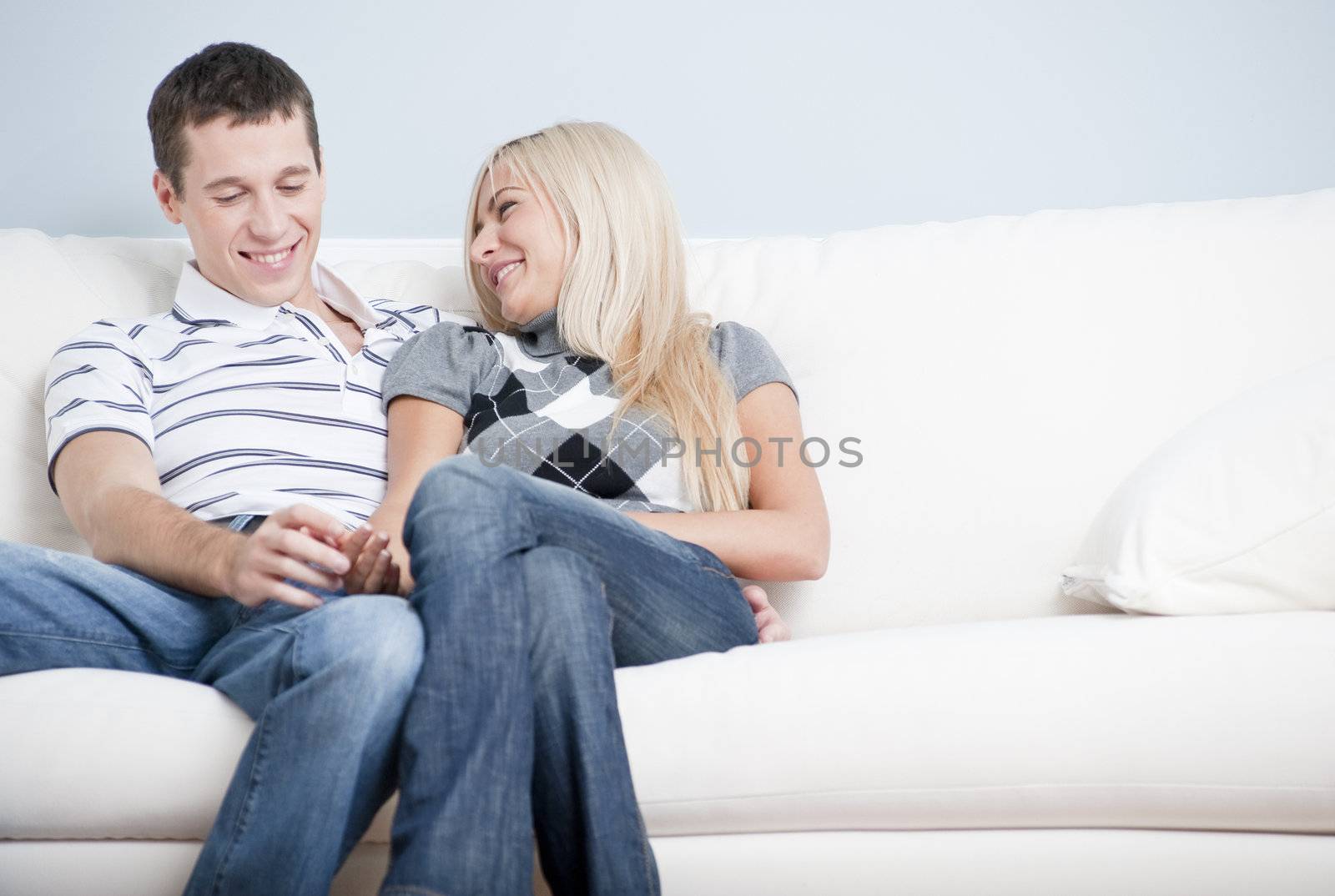 Cropped view of affectionate couple laughing and relaxing together on white couch. Horizontal format.