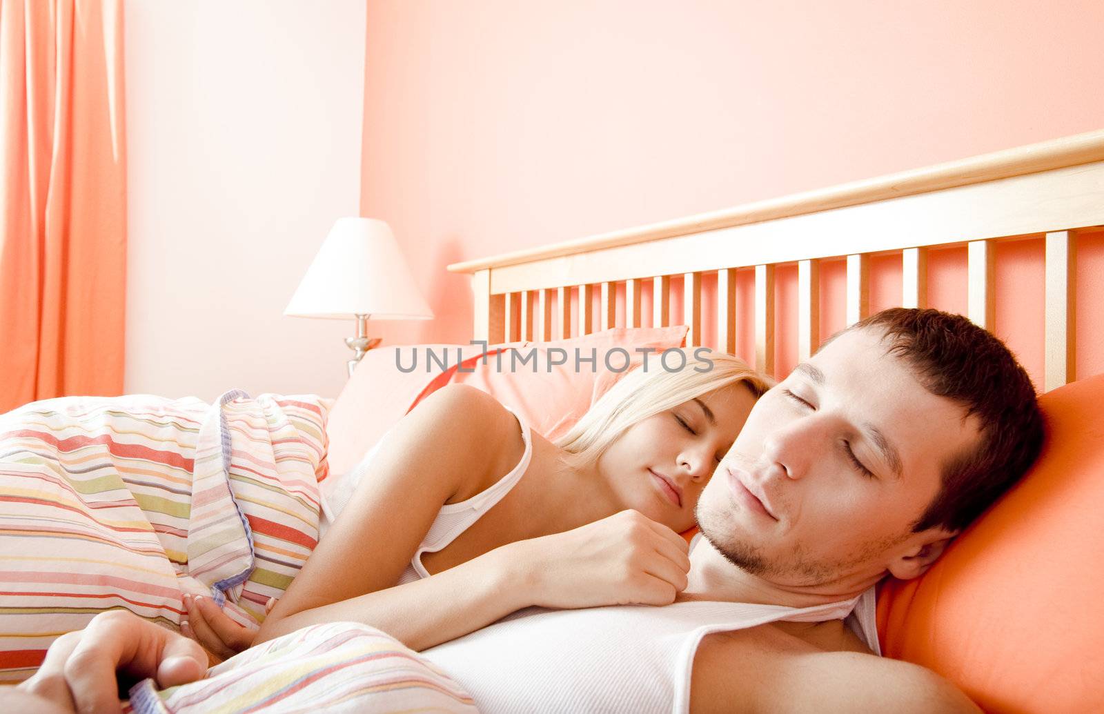 Man and woman sleep close together in a brightly-colored bedroom. Horizontal format.