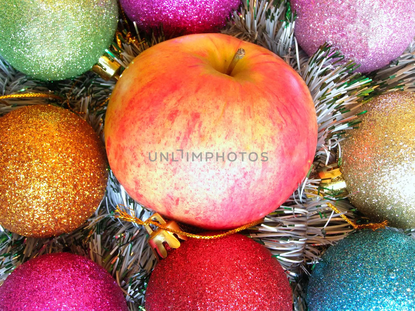 Apple among varicolored christmas-tree decorations