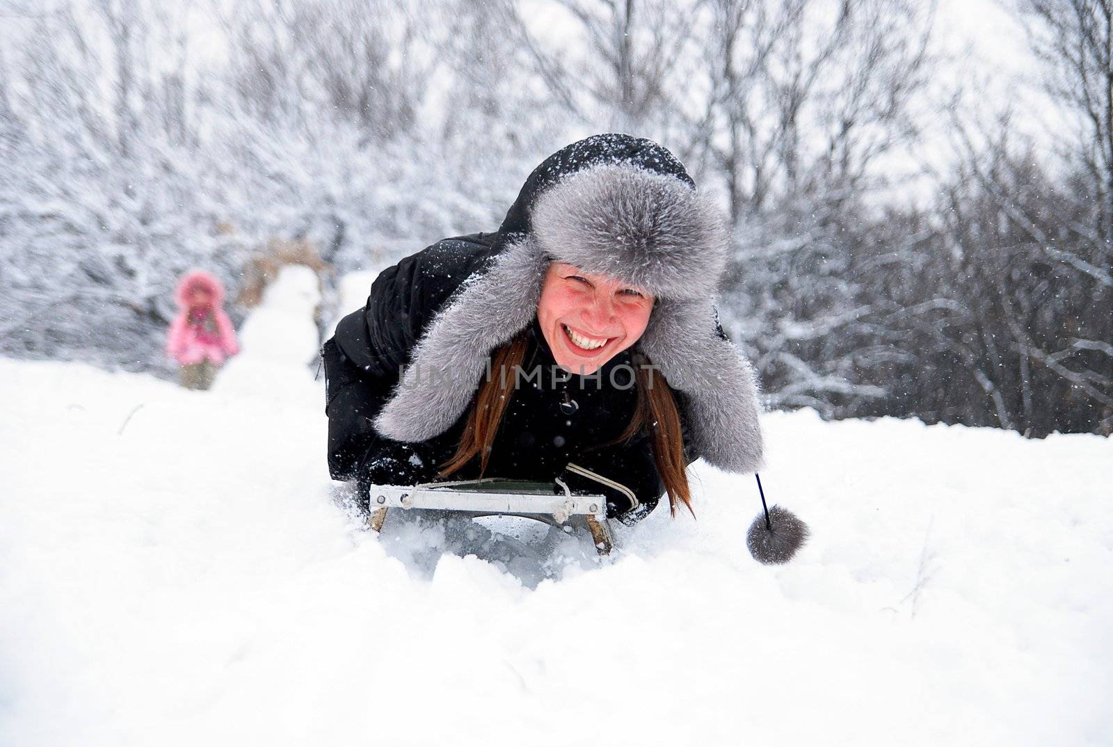 laughing girl in winter clothing goes down on sleds down the hill