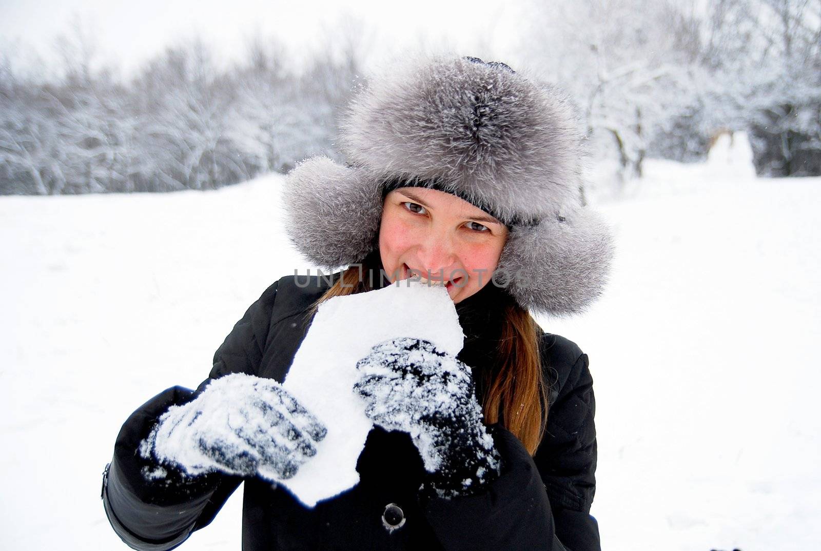 beautiful girl in winter clothing eating ice in the winter woods