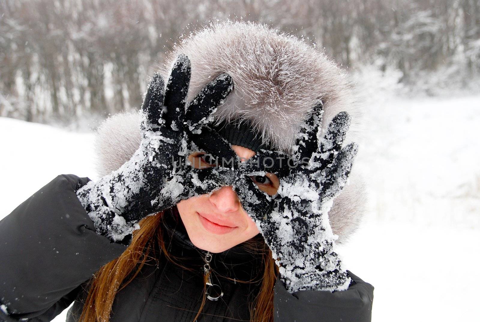 beautiful girl in winter clothing holds her hands like sunglasses