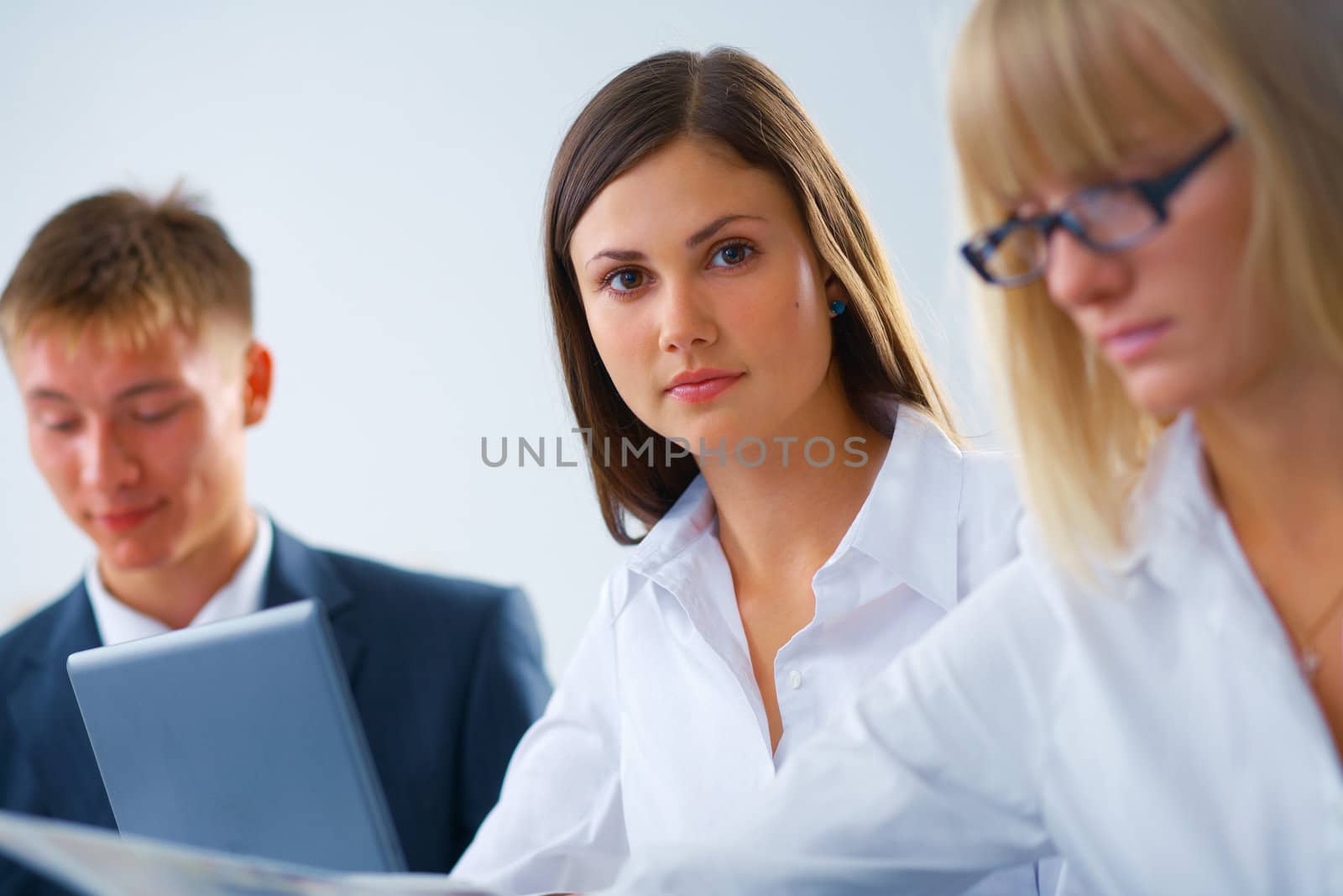 Portrait of young serious working woman with her colleagues