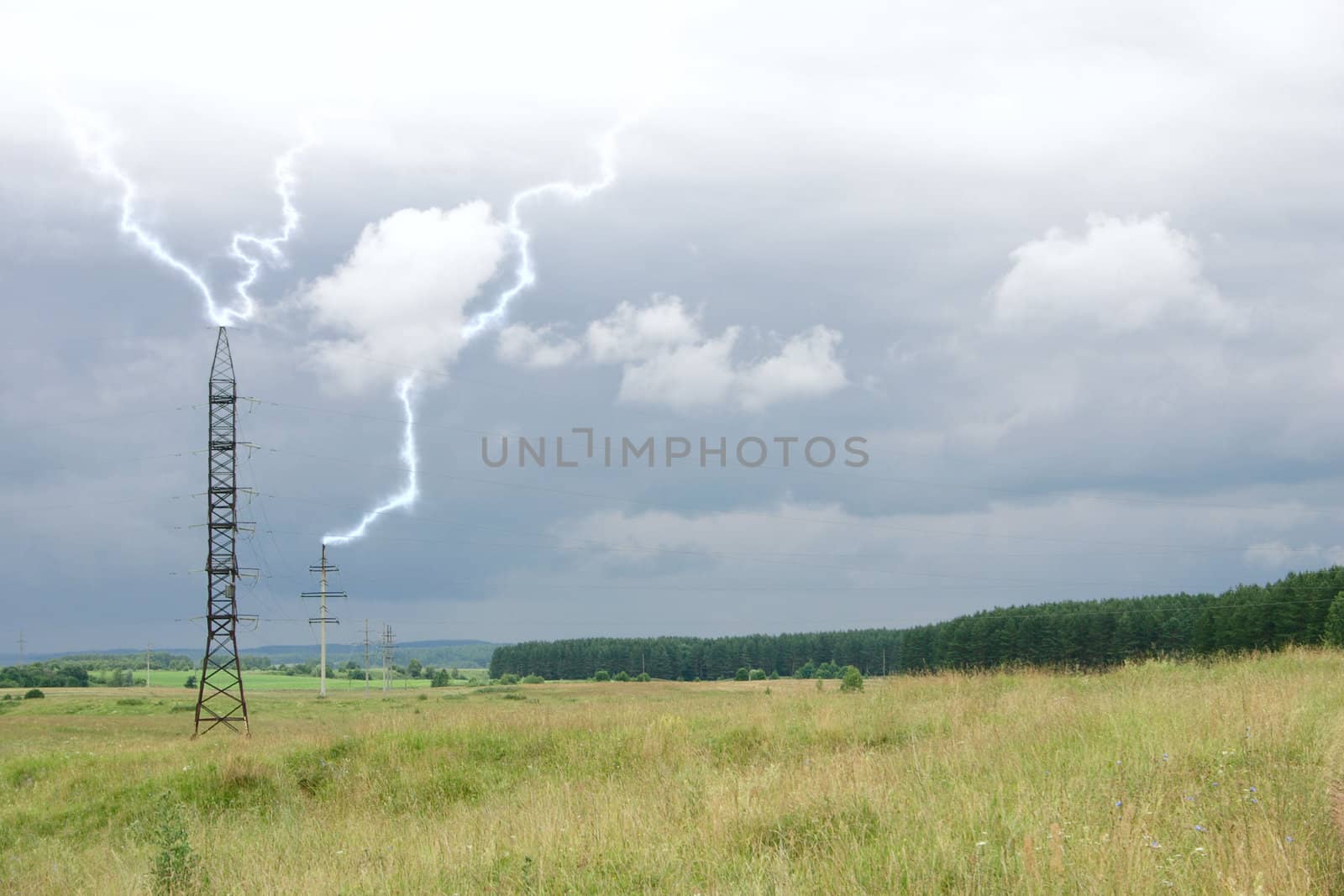 Electric mains passing through a field removed against the storm sky