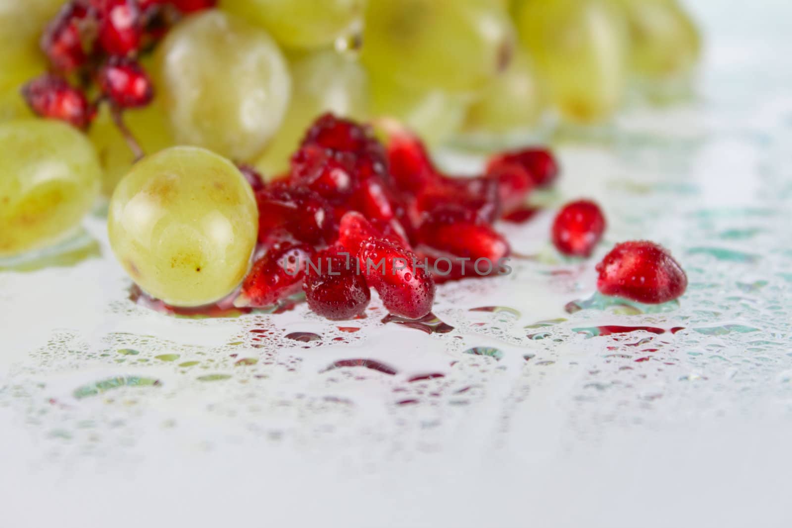 Grapes with pomegranate grains on glass removed close up