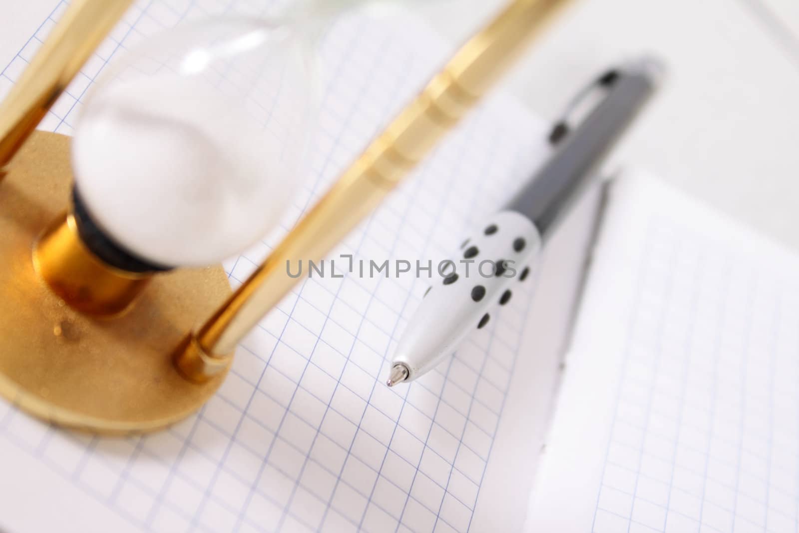 Part of a sand-glass on a notebook with the pen removed close up