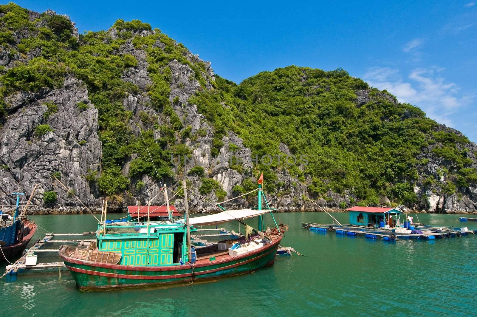 Wooden boat near one of the many fish farms located at Ha Long Bay.