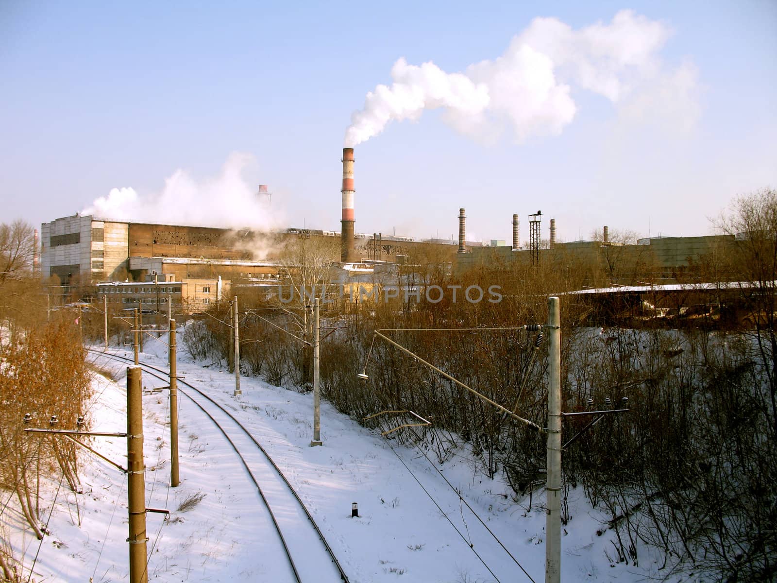 Rail bed coated by a snow near a metallurgical plant with smoking funnels, (look similar images in my portfolio)
