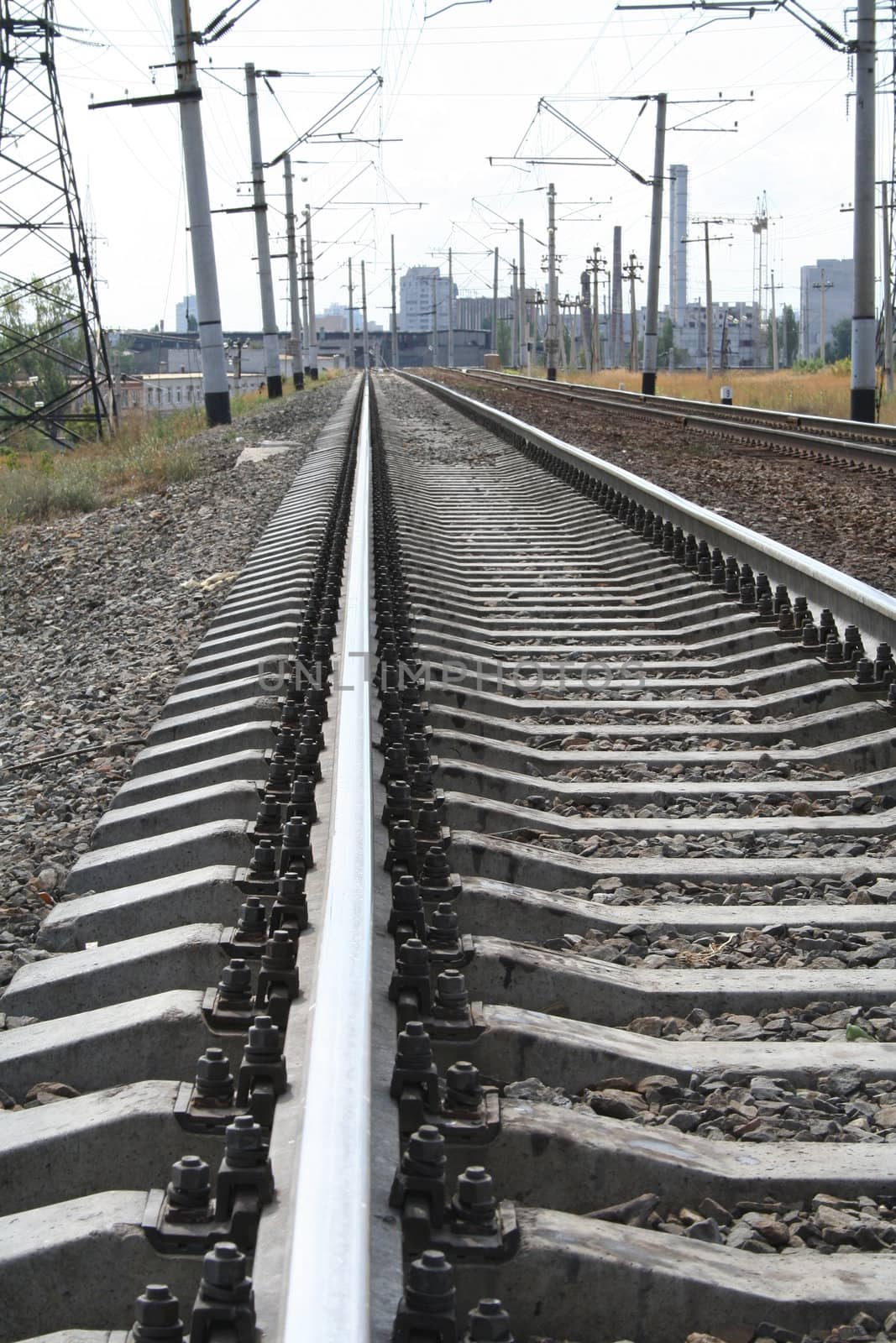 Railroad tracks, rails, cross ties, rubble and wires on a background of city, (look similar images in my portfolio)