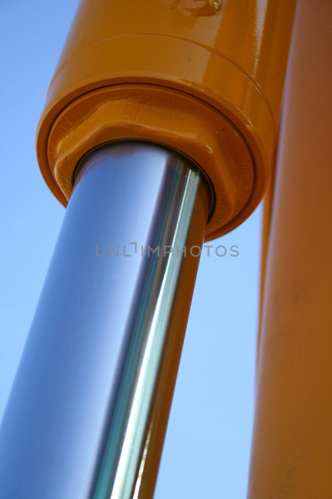 The chromeplated piston of hydraulic system of a dredge on a background of the blue sky, Isolated (look similar images in my portfolio)