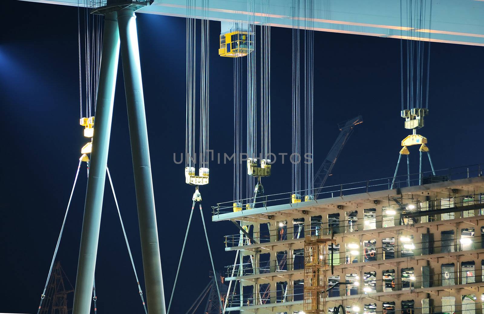 Detail of cranes and hooks in a shipyard by night