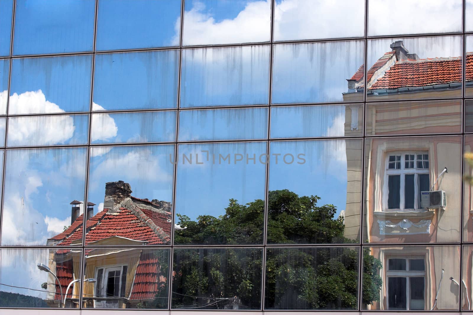 Old houses reflected in windows of  office building