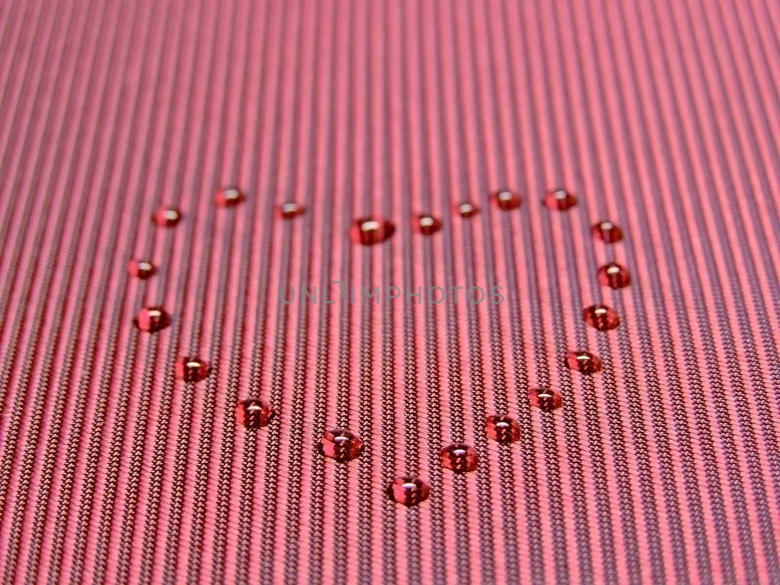 heart from water drops on the red fabric