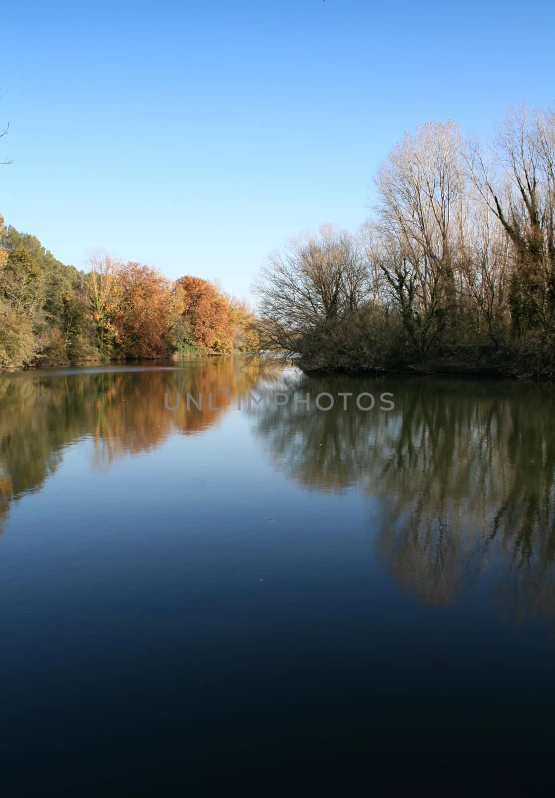 Landscape of a river on autumn, beautiful reflections and colors. Clean blue sky
