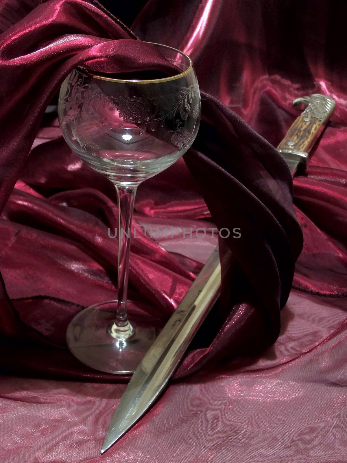 broken wineglass from crystal and bayonet among dark red tissue