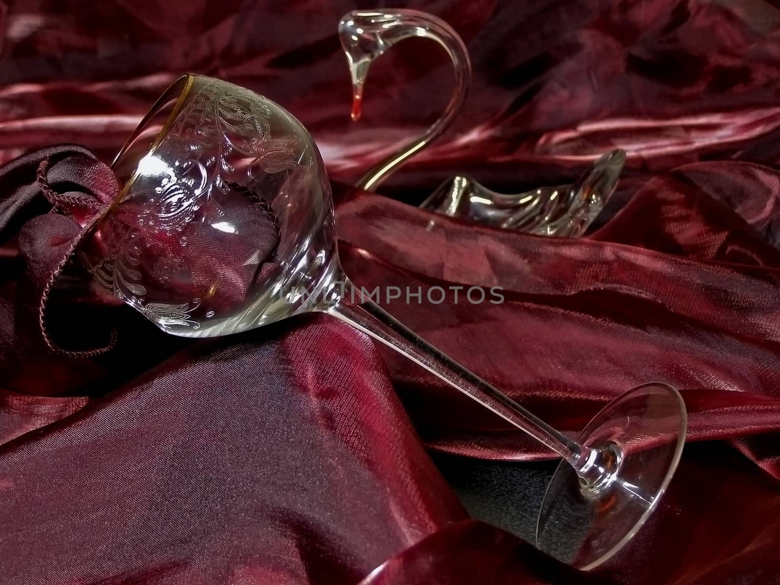wineglass from crystal against red tissue and swan figure         