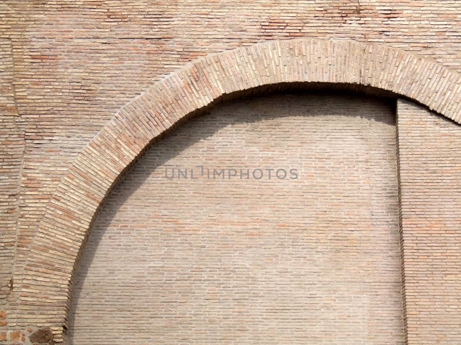 Interesting shapes on an old brick wall with an arch. Rome architecture.