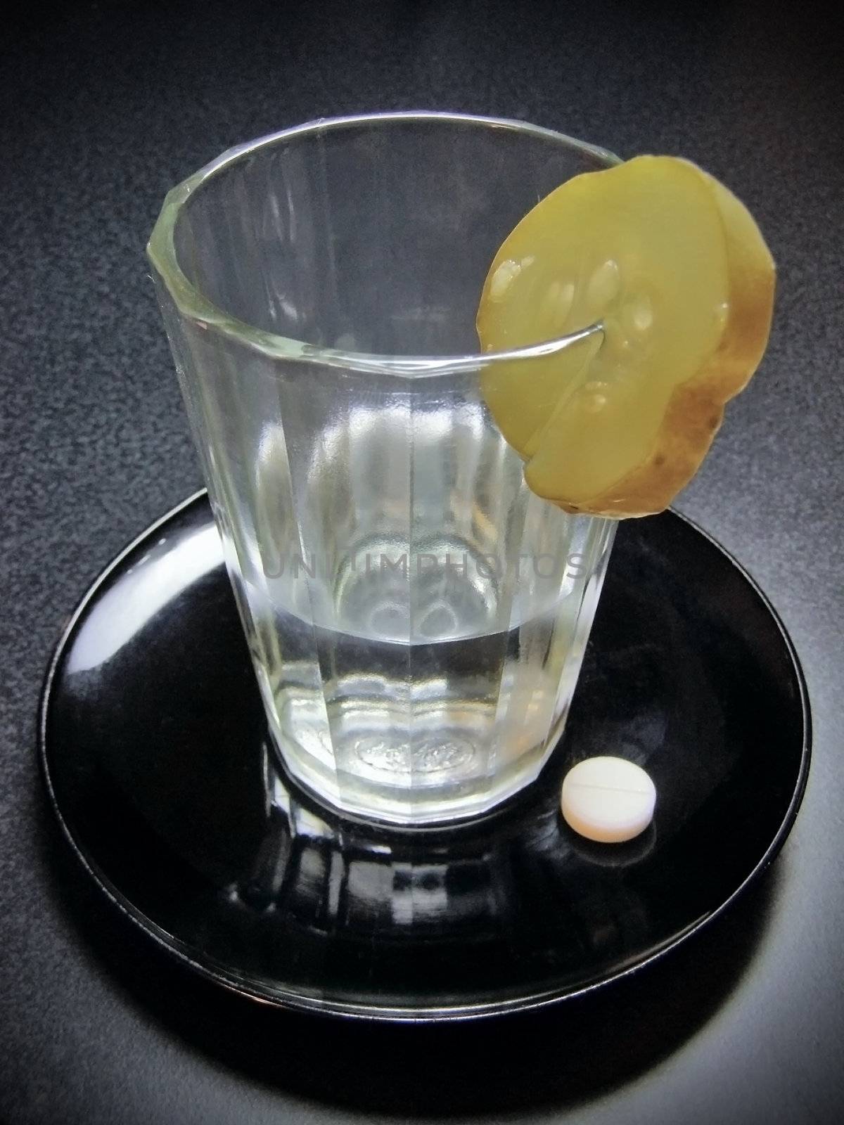 Glass of alcohol with cucumber and tablet on the saucer      