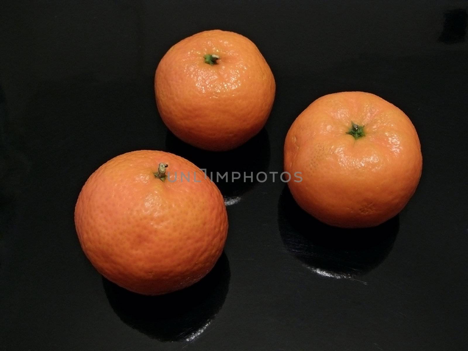 Three orange mandarines against the black background    