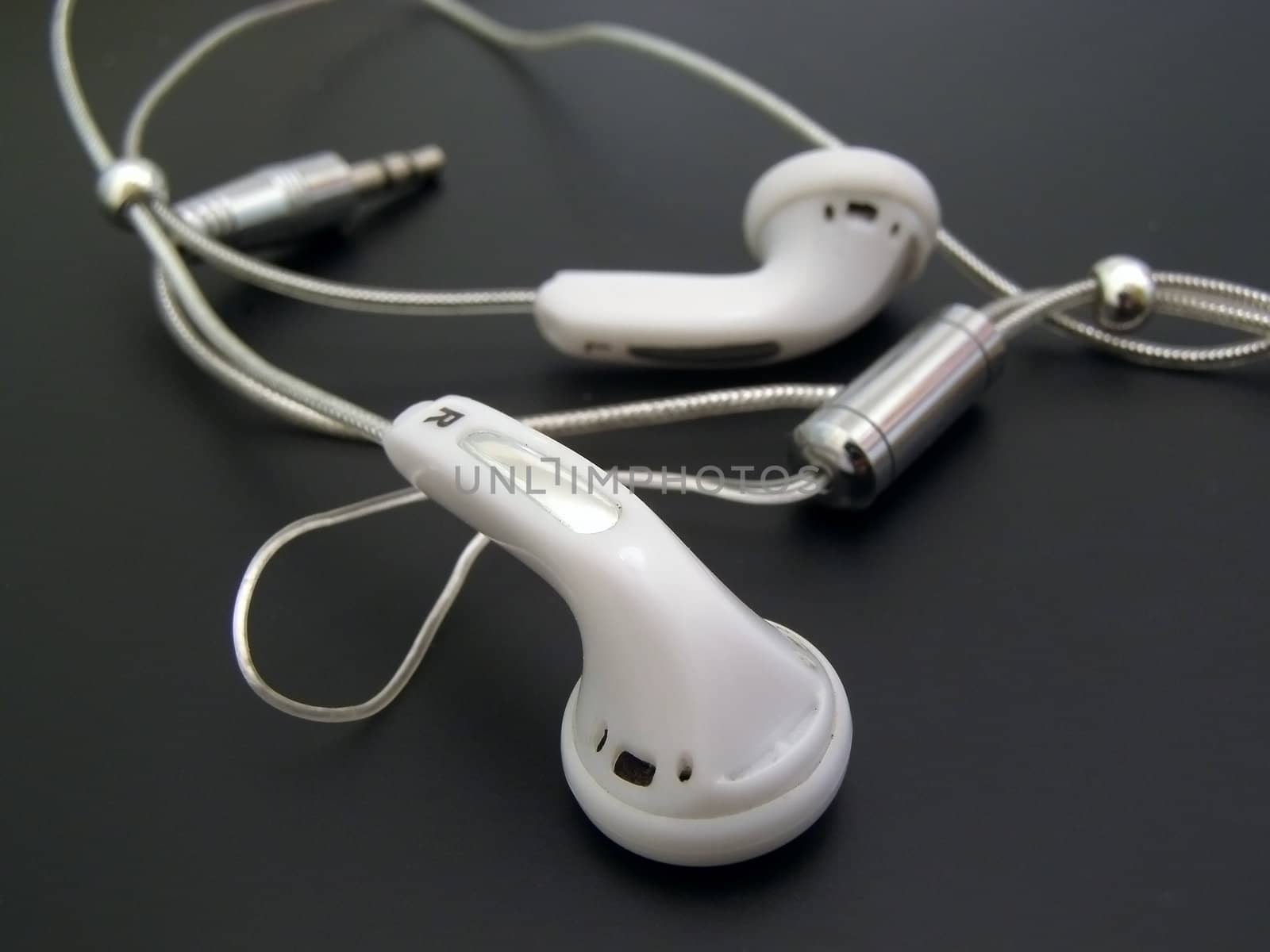 White earphones with cable against the black background  