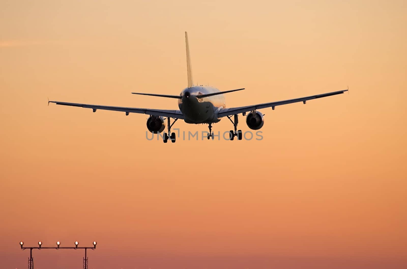 Airliner landing at sunset by photopierre
