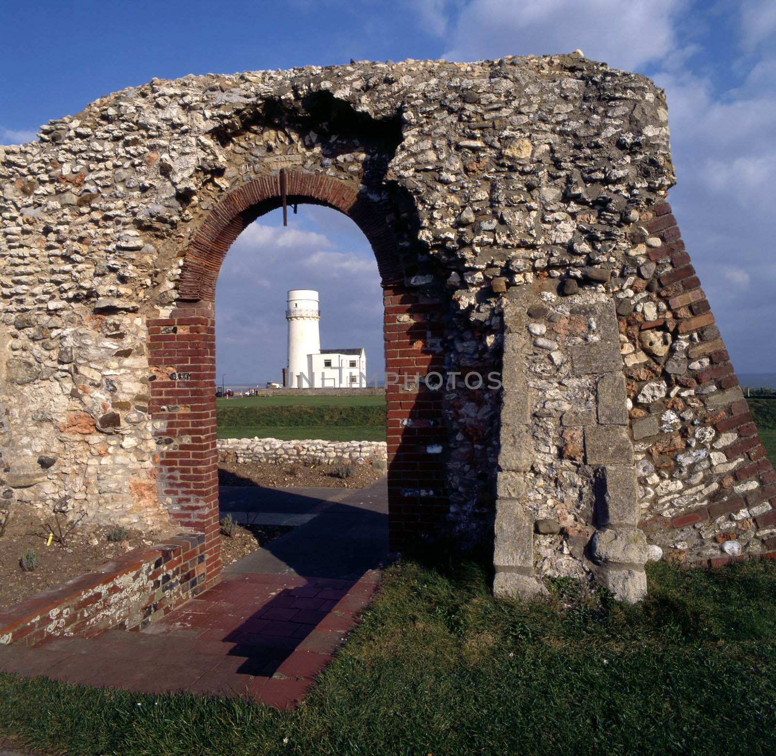 Lighthouse framed by the ruins of an old building