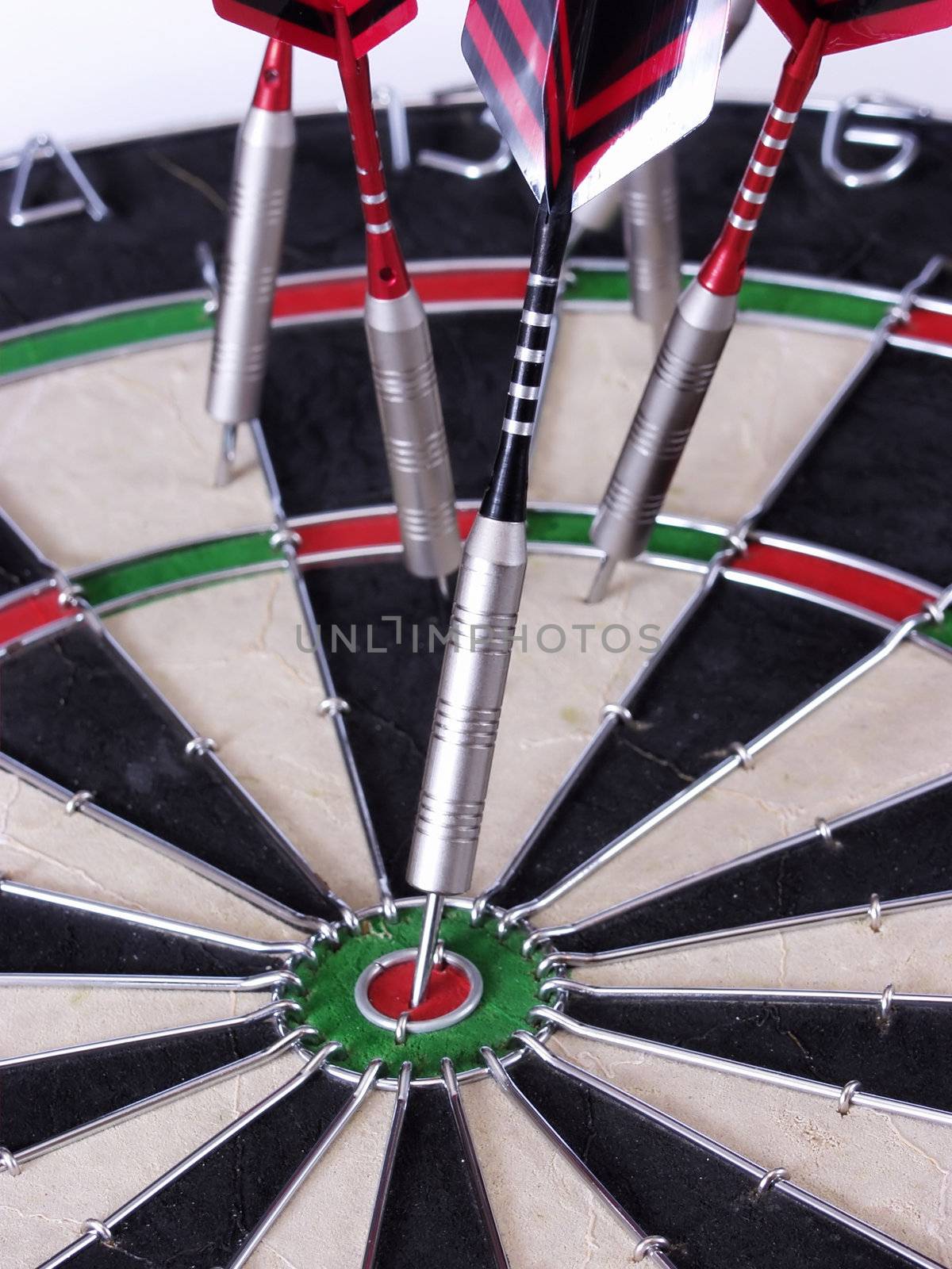 A close-up of steel tipped darts in a dartboard, one with a bullseye