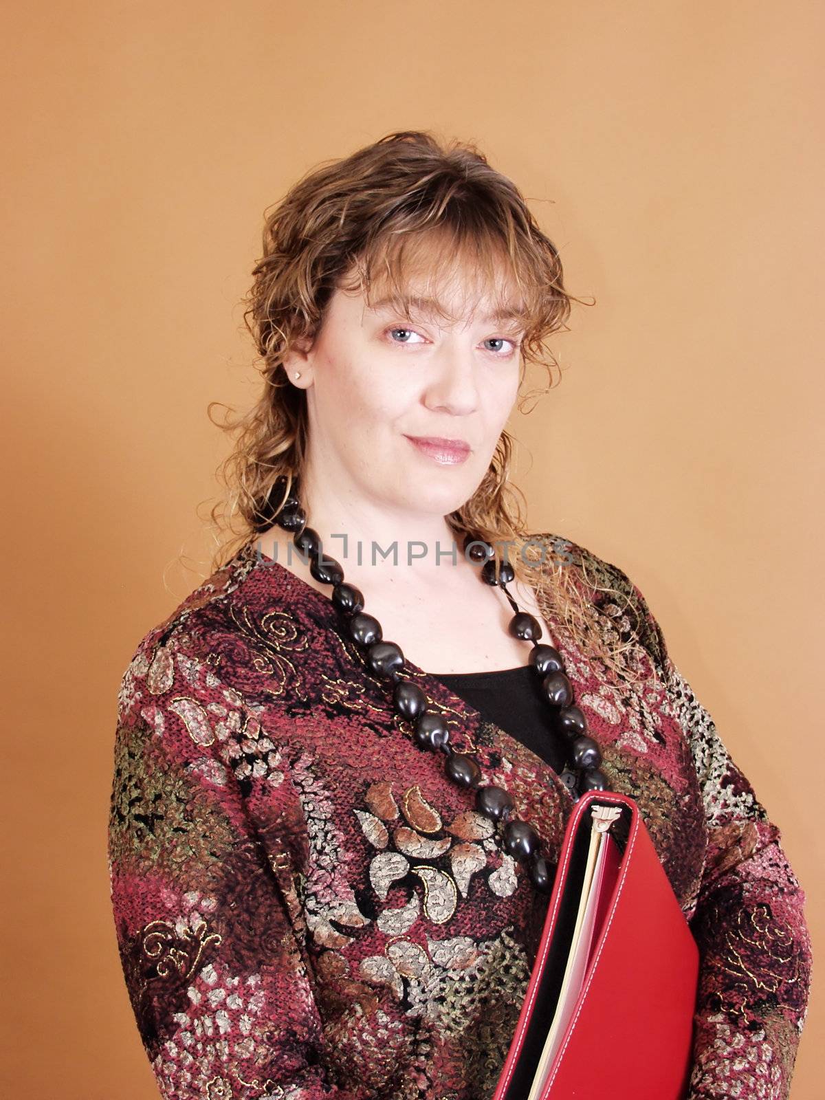 A successful businesswoman holding a red notebook. On solid tan background.