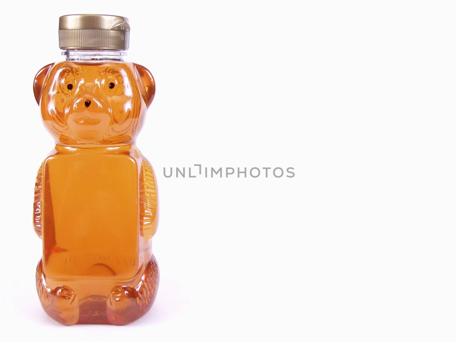 A bear shaped container of honey, off center with room for text on bear bottle and background. Over a white background.
