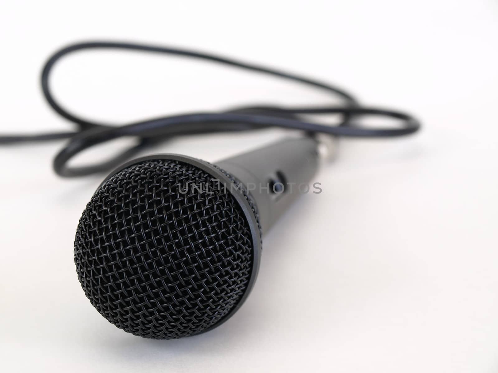 Studio microphone isolated on a white background with cord trailing off to the side.