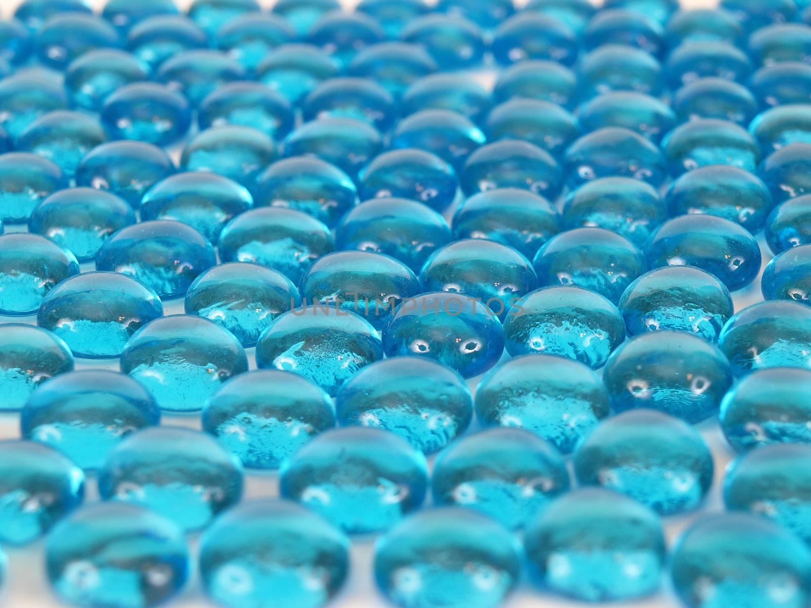 Blue glass beads taken in side shot, white highlights make eyes on faces.