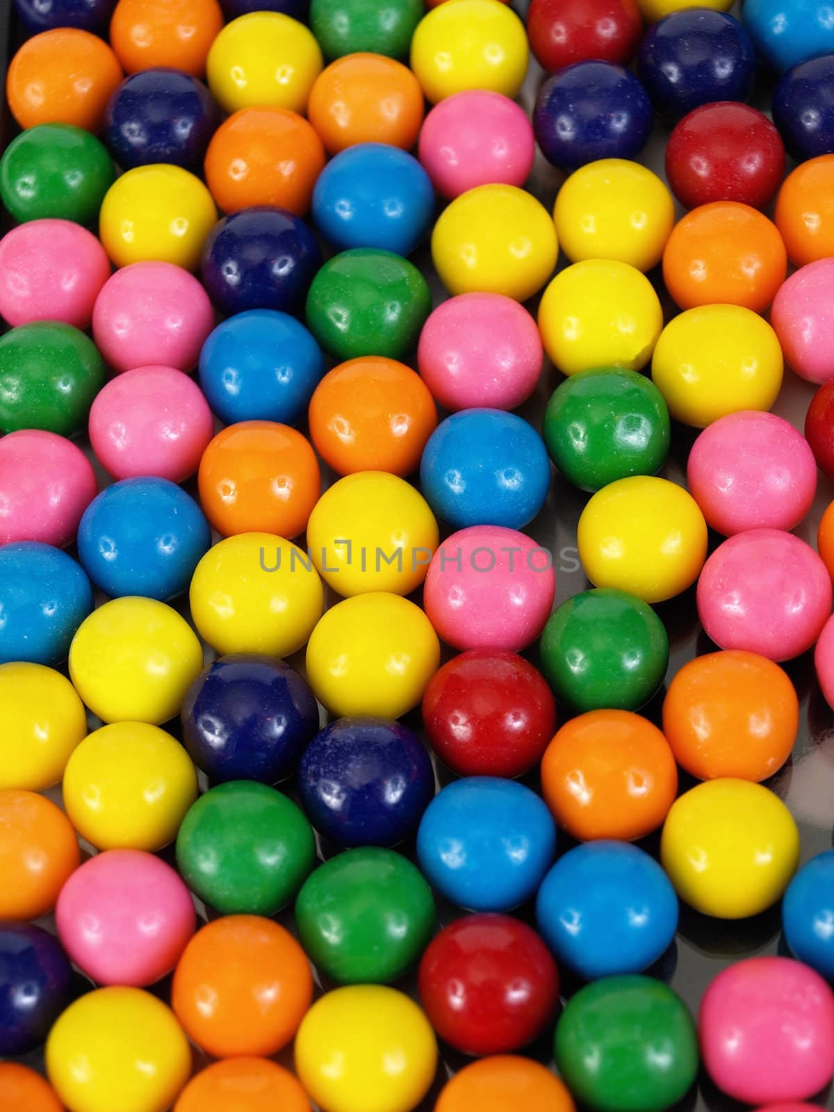 A colorful variety of gumballs in a close but random pattern.