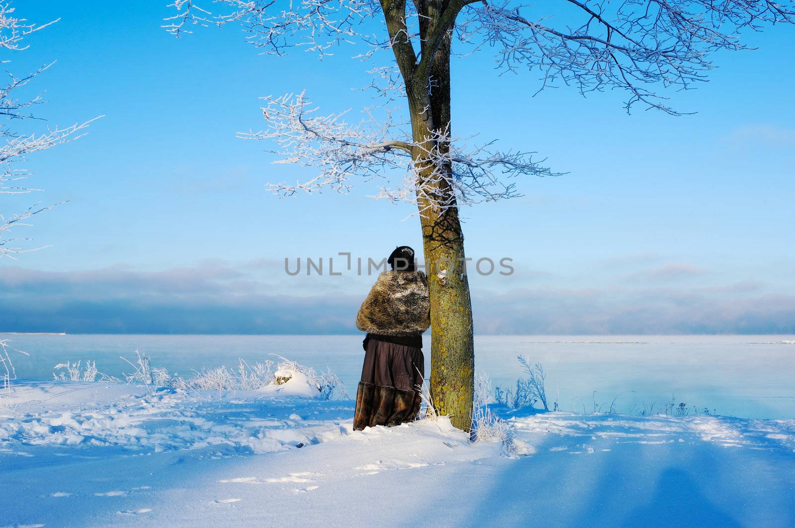 Woman near the tree against the background of winter sea