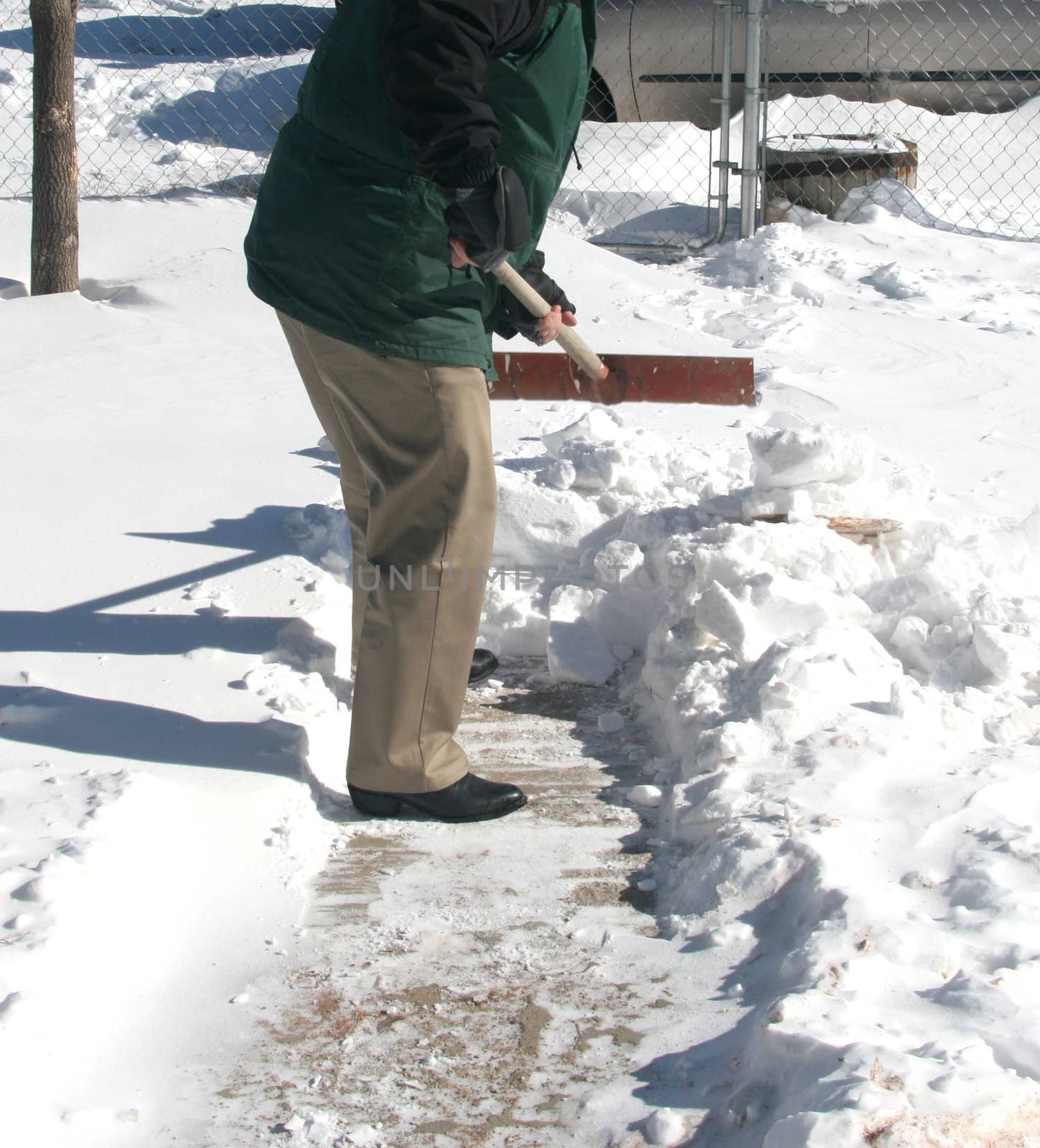 Homeowner shoveling snow on front walkway after winter storm to get to snow-covered driveway.