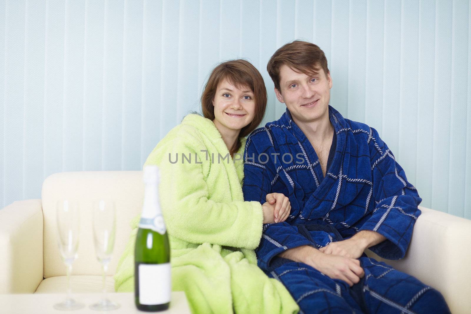 Young happy couple with sparkling wine on sofa
