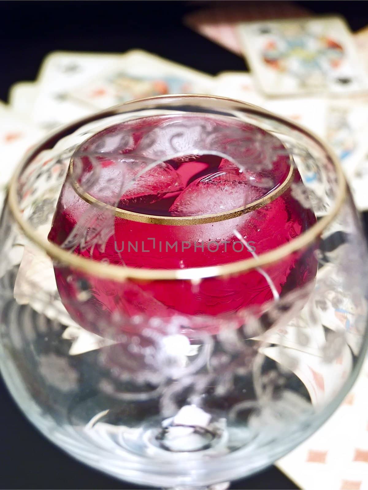 Wineglass with the red and plaing cards on the table tgrough broken glass