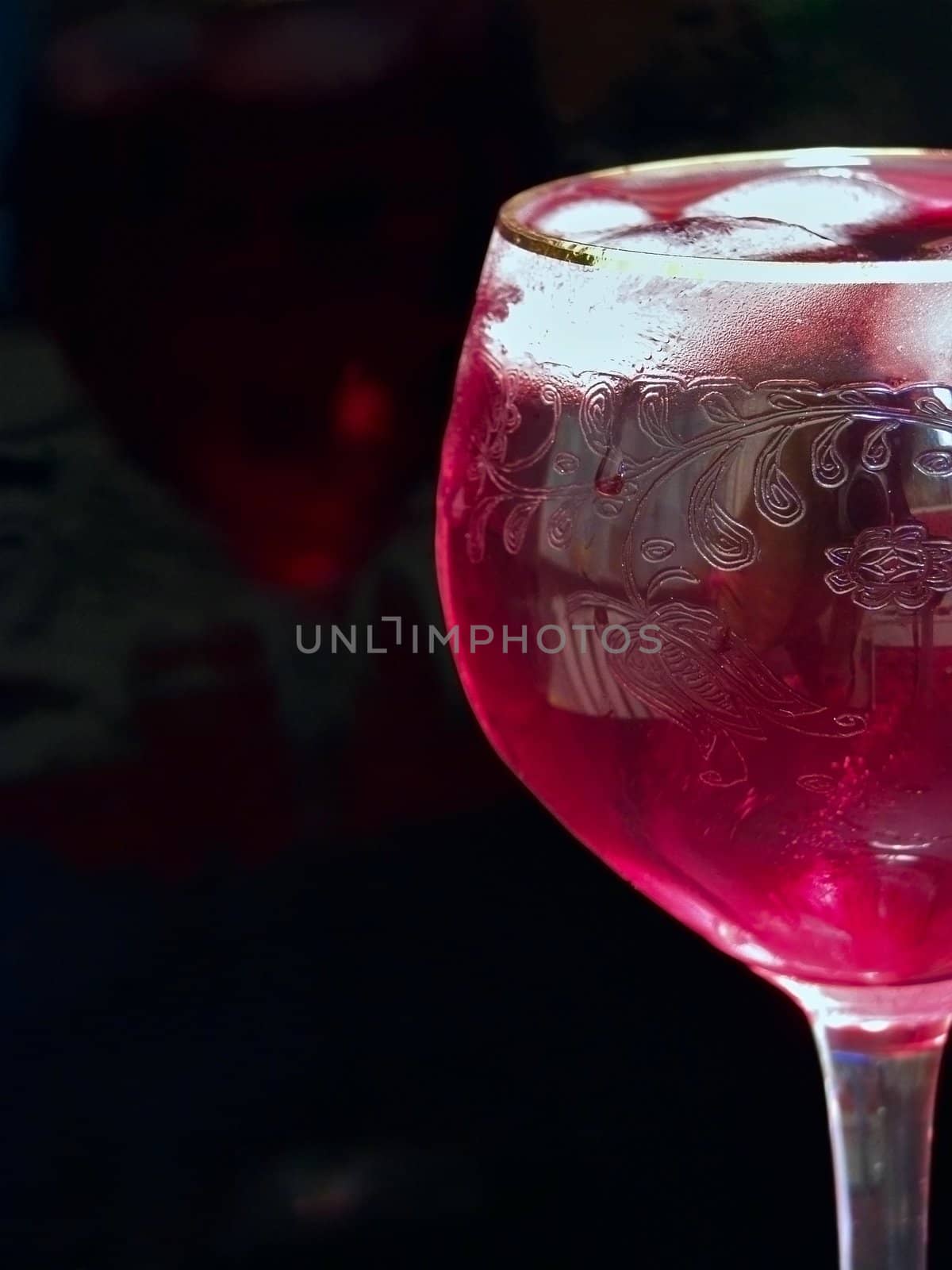 Half of wineglass full of red wine with ice