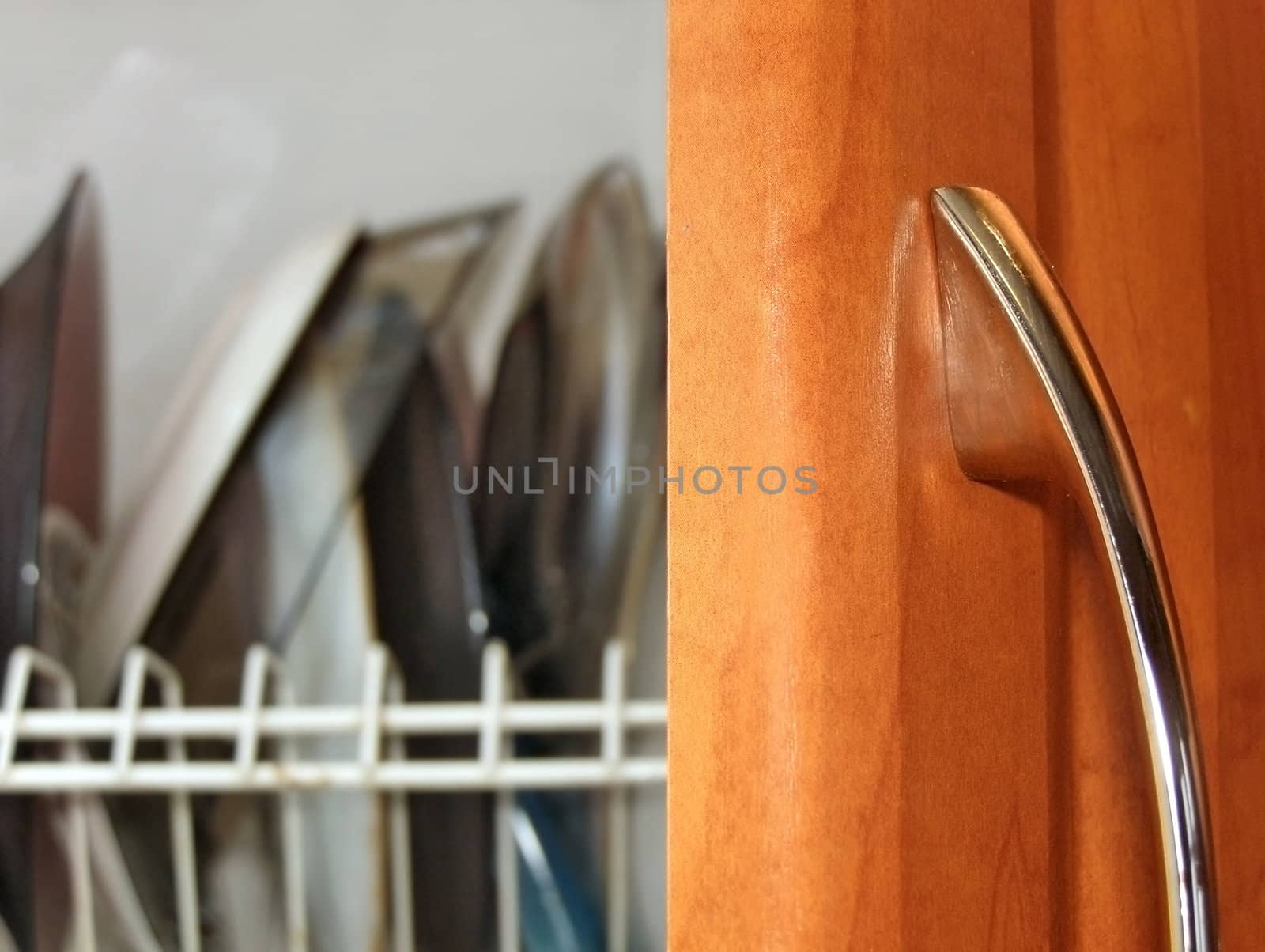 Kitchen plates over open wooden door with metallic handle