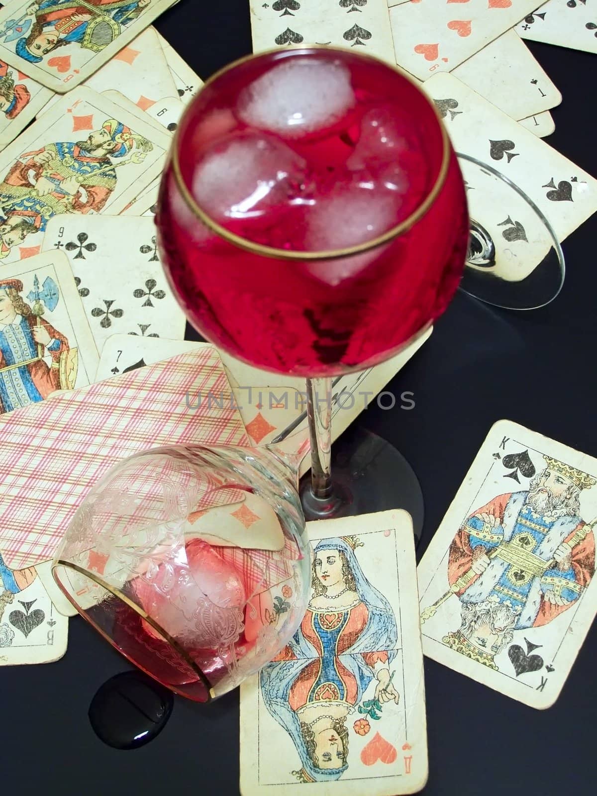 Wineglass with the red and plaing cards on the table with broken glass