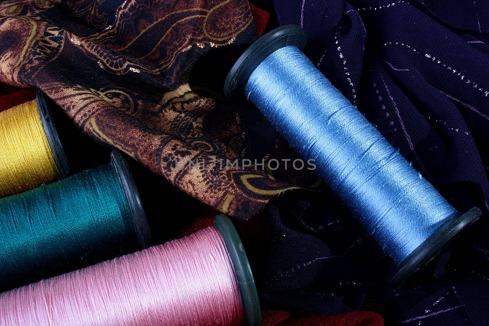 The big coils with threads of different colouring against coloured rags from a fabric.