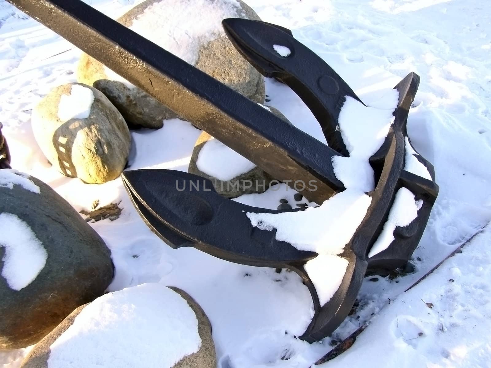 Winter iron anchor with the stones and snow