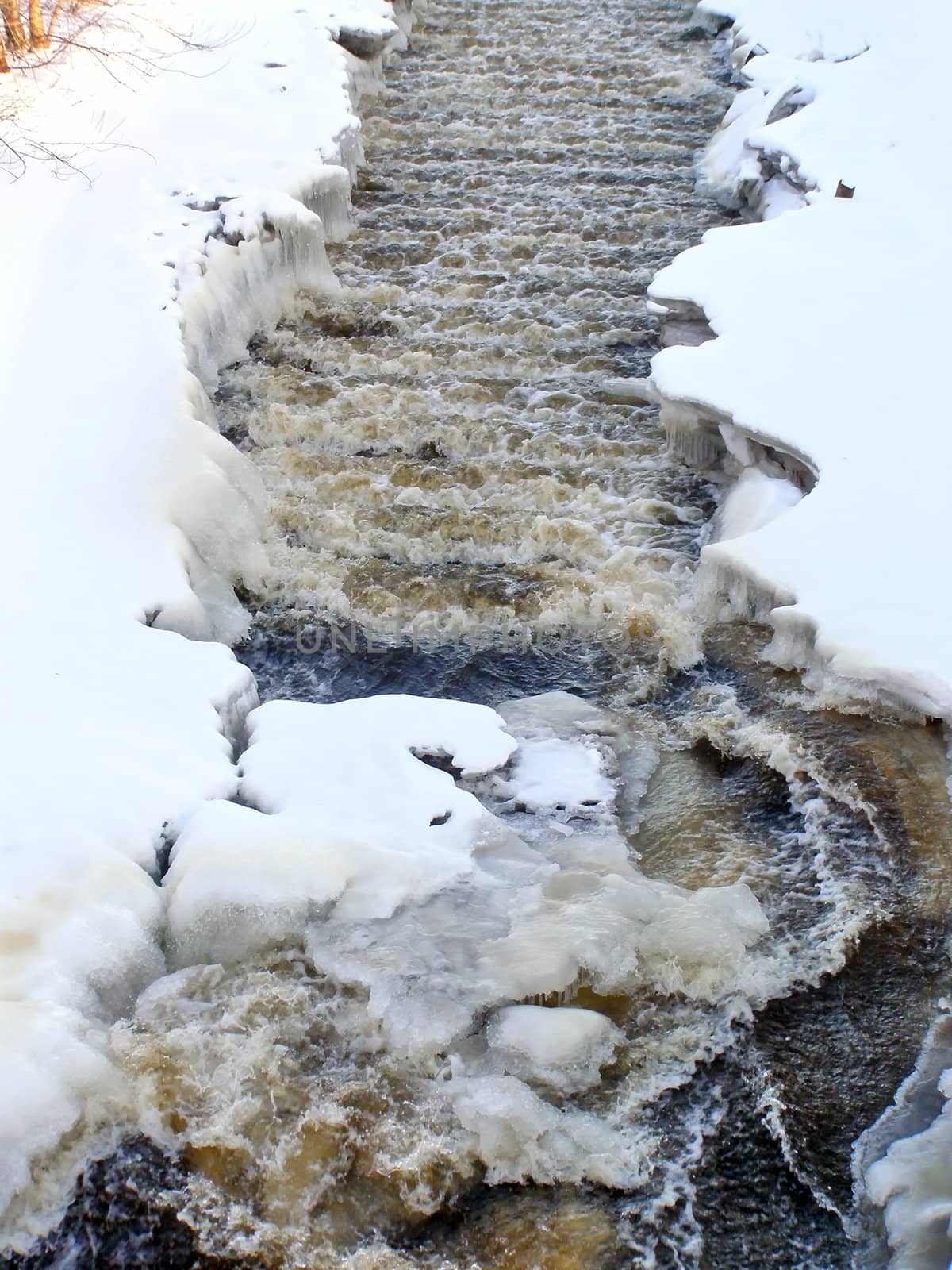 The stream of water run through the snow 
