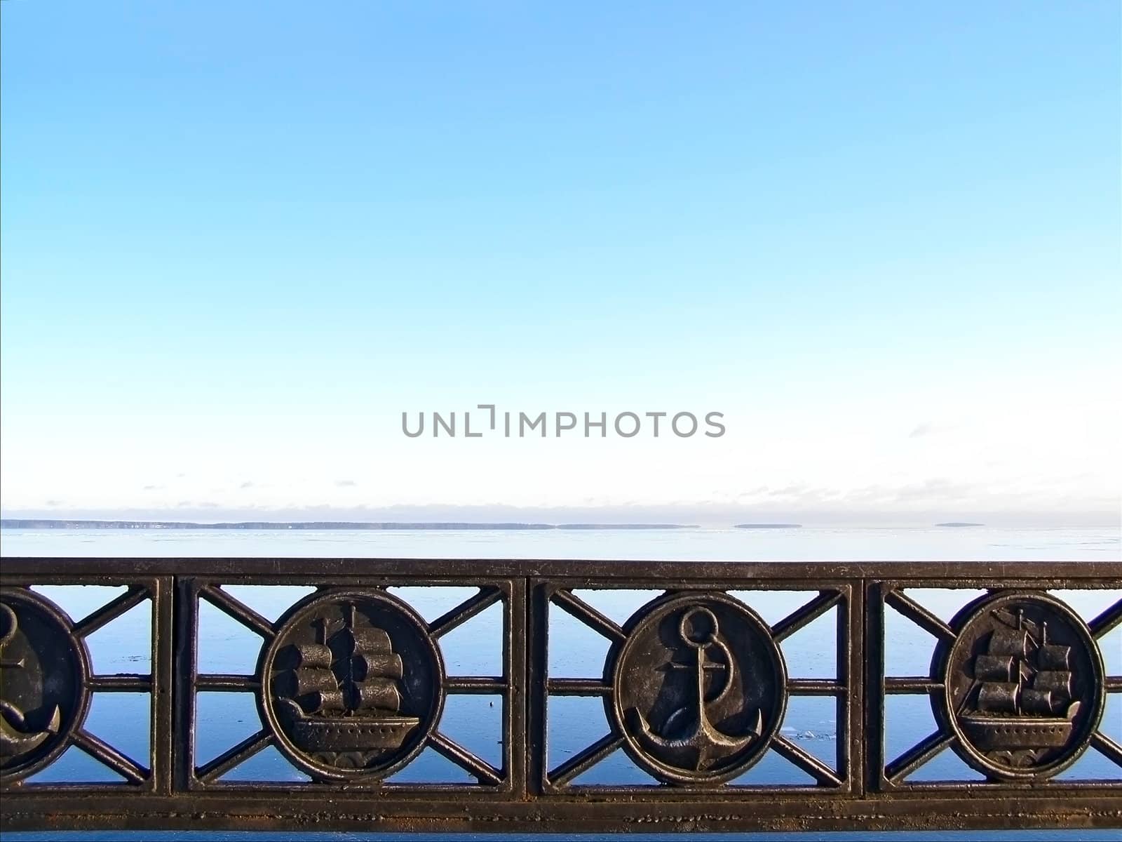 Tranquil water skyline with the blue sky and metal decorated barrier