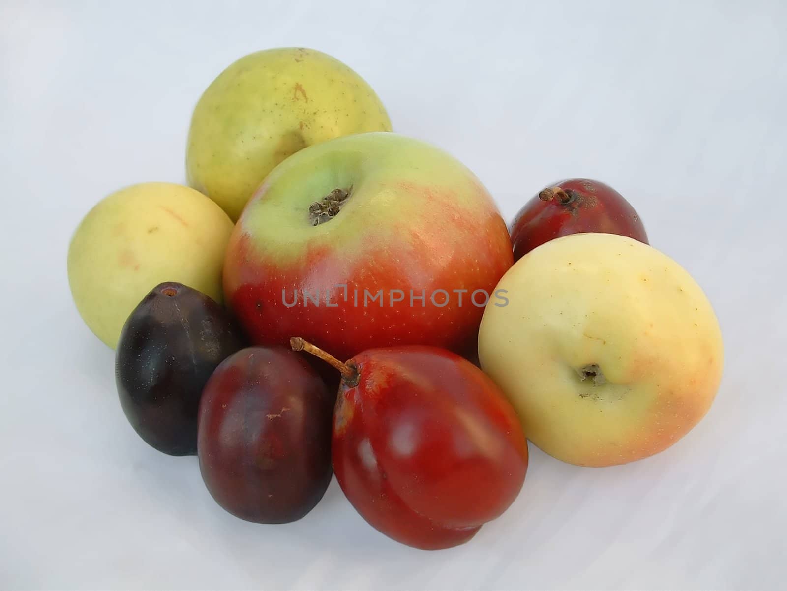 The natural ripe tasty not modified fruit apples and plums on a white background