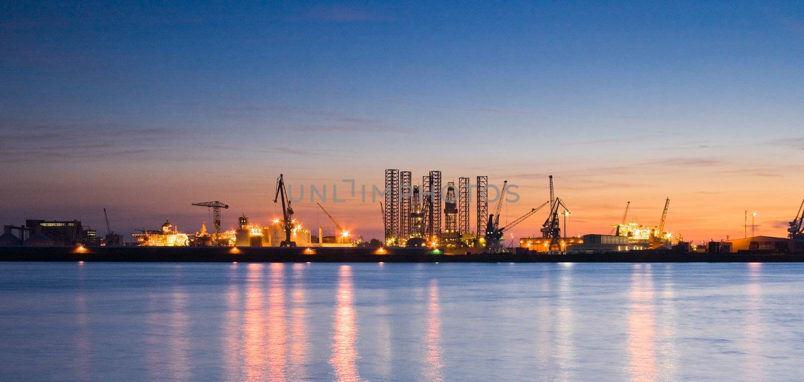 A blue sky and industrylights with reflection after sunset at the river